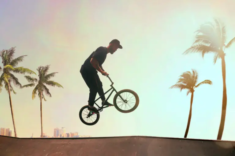 BMX rider is performing tricks in skatepark on sunset.