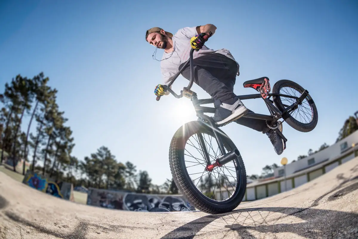 Bmx stunt performed at the top of a mini ramp on a skatepark.