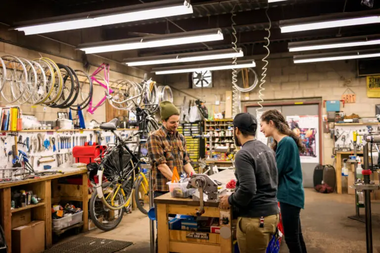Mid-adult man talking with customers in bicycle shop