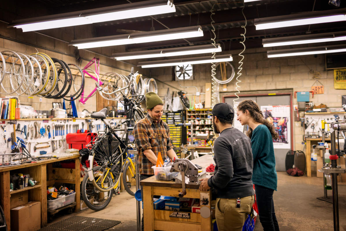 Mid-adult man talking with customers in bicycle shop