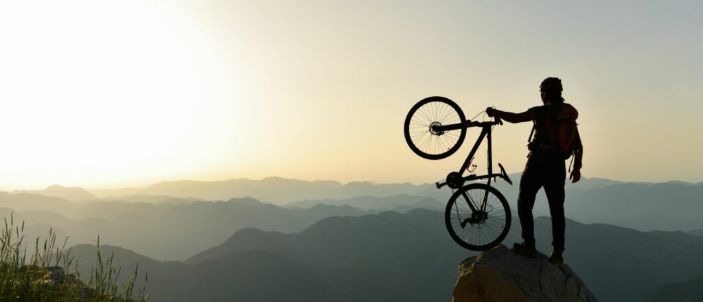 image of a man holding a bike atop a mountain